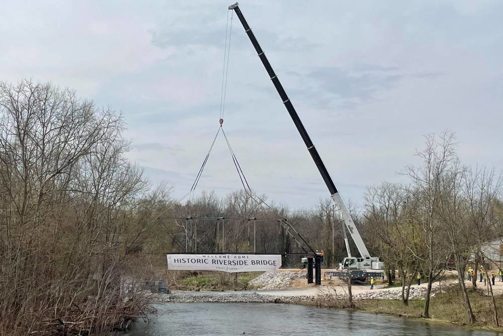 Crews raise the 112-year-old Riverside Bridge onto new trusses near the Ozark Mill, just downstream from where it originally crossed the Finley River.